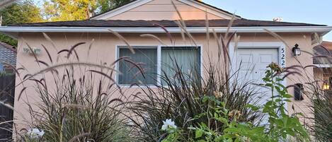 A single-story house with a beige exterior, a white door, and a window.