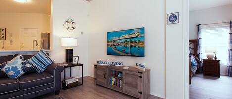 A living room with a sofa, a coffee table, a side table, a bookshelf, and a painting of a train on a bridge.