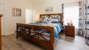 Een slaapkamer met een houten bed, een nachtkastje, een muur met een 'love' bord en een raam met gordijnen.