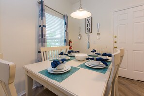 A dining area with a white table set for four, blue placemats, and a 'YUM' sign on the wall. - Jay's Beach Disney Villa - South Facing Pool (Davenport)