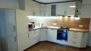 A modern kitchen with white cabinets, a microwave, a sink, and a stove. - Ferienwohnung in Odenthal (Odenthal)