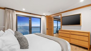 A bedroom with a large bed, a TV mounted on the wall, and a sliding door leading to a balcony with a view. - SA Beach Suite 6 by Stay Awhile Villas (Malibu)
