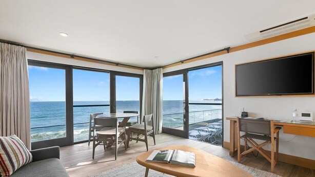 A modern hotel room with a large balcony, a flat-screen TV, a dining area, and a sofa. - SA Beach Suite 6 by Stay Awhile Villas (Malibu)