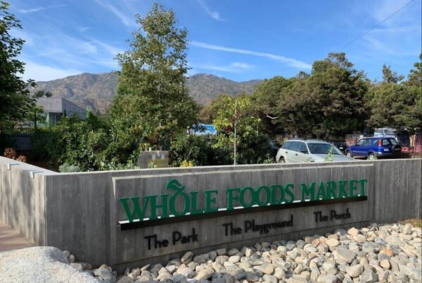 A sign for Whole Foods Market with a view of mountains and parked cars.