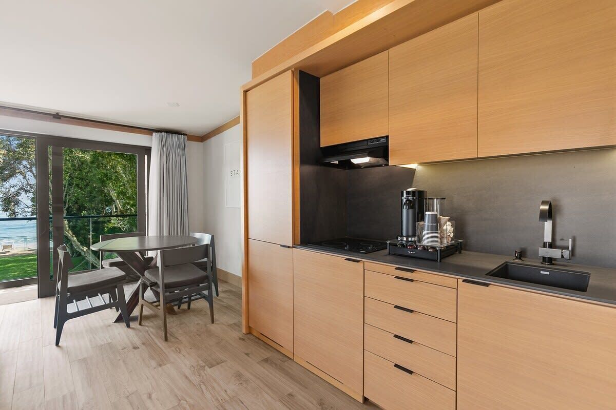 A modern kitchen with wooden cabinets, a black stove, and a coffee machine.