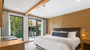 Un dormitorio moderno con una cama grande, un escritorio y un ventanal corredero que da a un espacio exterior.
