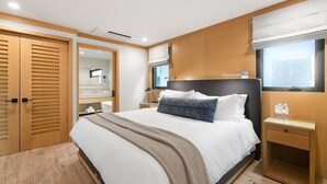 Et moderne hotelværelse med en stor seng, et træskab, et sengebord og et vindue med skodder.