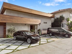 Une maison moderne à deux étages, avec un garage, une voiture et un fourgon garés devant.