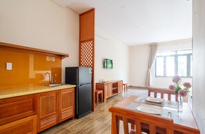 A compact kitchen with wooden cabinets, a black refrigerator, and a dining area with a table and chairs.