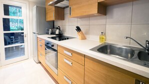 Eine moderne Küche mit Holzschränken, einem Edelstahlspülbecken und einem eingebauten Backofen.