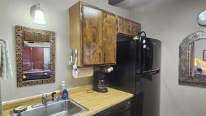 A kitchen with wooden cabinets, a black refrigerator, a coffee maker, and a sink. - Close to the Lifts, Sleeps Up to 8, Windows and Deck with Ski Mountain Views (Angel Fire)
