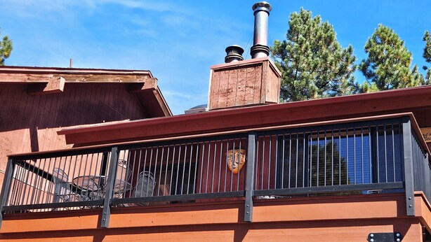 A building with a wooden facade, a balcony with metal railings, and a chimney. - Close to the Lifts, Sleeps Up to 8, Windows and Deck with Ski Mountain Views (Angel Fire)