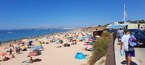 A crowded beach with numerous umbrellas and people.