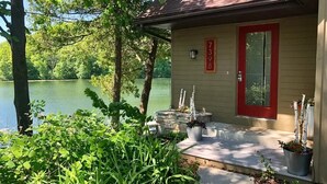 A house with a red door, number 7398, near a lake surrounded by greenery. - Walk to Road America Races. Enjoy the lake frontage and fishing and kayaking. (Plymouth)