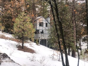 Eine Hütte mit Balkon, umgeben von Bäumen und Schnee.