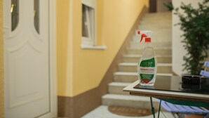 Una botella de desinfectante para manos sobre una mesa en un pasillo con una escalera al fondo.