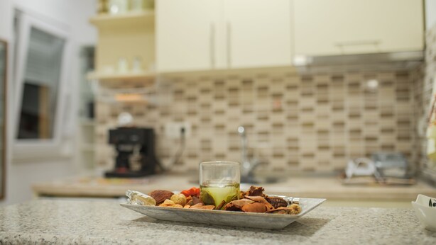 Una encimera de cocina con una bandeja de frutos secos y un vaso de bebida verde.