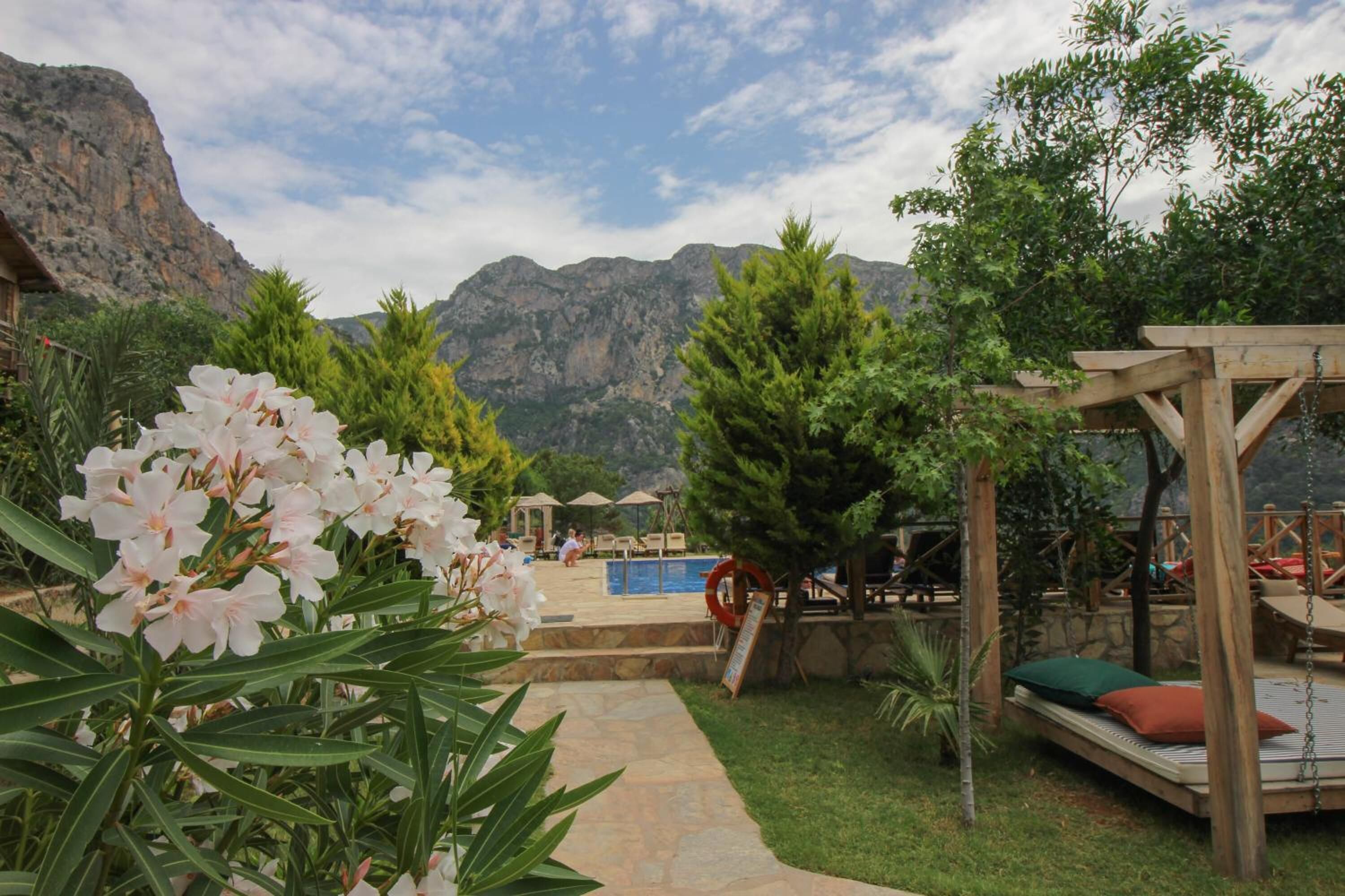 A resort with a pool, outdoor seating, and a mountainous backdrop.
