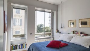 A bedroom with a large bed, a red pillow, and a bookshelf. - Suite Blu a Genova by Wonderful Italy (Genova)