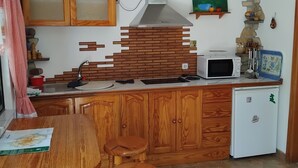 Une cuisine avec des meubles de rangement en bois, une cuisinière encastrée, un four à micro-ondes et un petit réfrigérateur.