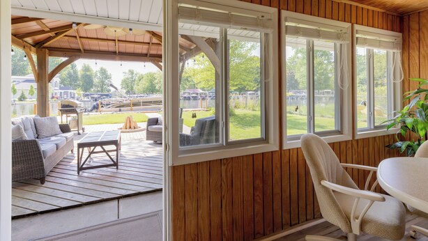 Un patio techado con piso de madera, un sofá, una mesa y una silla.