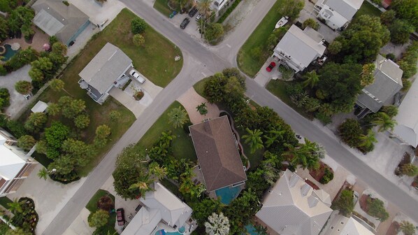 Luchtbeeld van een woonwijk met huizen, een zwembad en een grote boom.
