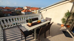 Ein Balkon mit Tisch und Stühlen, Blumentöpfen und Blick auf die Stadtlandschaft.