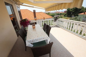 A balcony with a table and chairs, potted plants, and a view of buildings. - Comfortable Apartment for 5 Persons (Zadar)