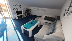 Ein Wohnzimmer mit einer Couch, einem Couchtisch und einem Fernseher.