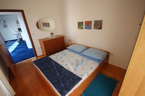 A bedroom with a wooden bed, a dresser, a mirror, and a small table with a lamp. - Comfortable Apartment for 5 Persons (Zadar)