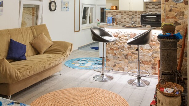 A spacious living area with a sofa, a round woven rug, and a kitchen in the background. - A home witha view Sky -attic (Mostar)