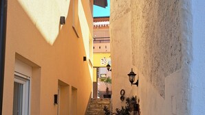 A narrow alleyway with a stone staircase leading to a building, white chairs, and a potted plant. - A home witha view Sky -attic (Mostar)