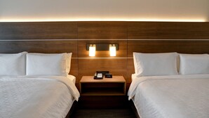 A hotel room with two beds, a wooden headboard, bedside lamps, a nightstand with a phone and clock, and a carpeted floor. - Holiday Inn Express & Suites Ottawa by IHG (Ottawa)