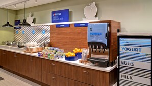 A breakfast area with a Squeeze the Day dispenser, a refrigerator with yogurt, eggs, and milk, and a sign for Express Start Breakfast. - Holiday Inn Express & Suites Ottawa by IHG (Ottawa)