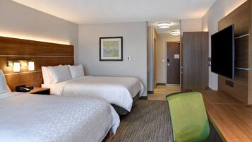 A hotel room with two beds, a desk, a chair, a television, and a framed picture on the wall.