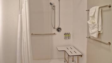 A shower area with a showerhead, handheld shower, and a small table with bottles.