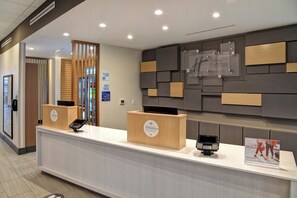 A hotel reception area with a modern design, including a reception desk, a digital check-in kiosk, and a wall-mounted sign indicating the property is a non-smoking Holiday Inn Express & Suites. - Holiday Inn Express & Suites Ottawa by IHG (Ottawa)