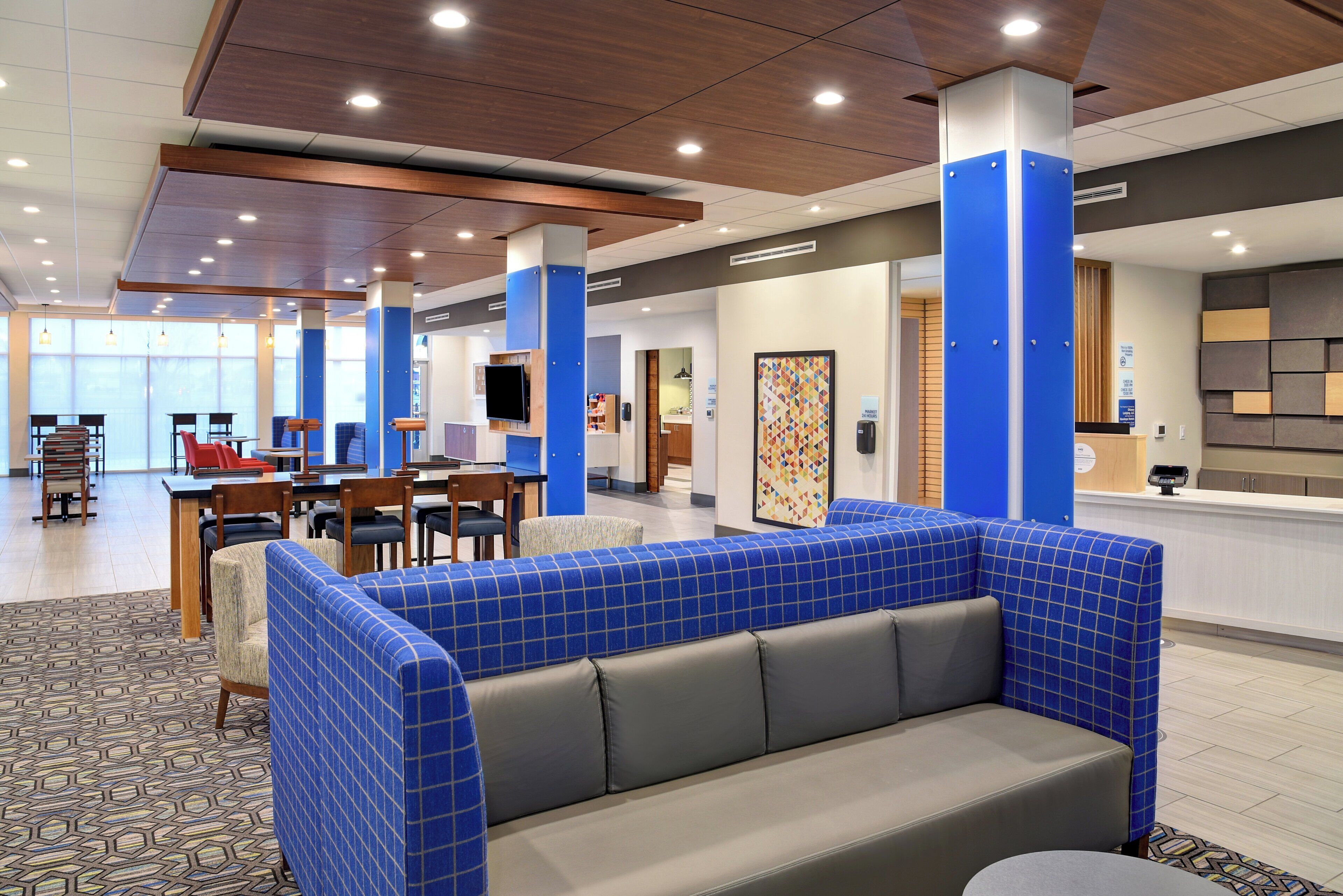 A hotel lobby with seating areas, a reception desk, and a view of the outside.