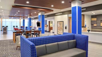 A hotel lobby with seating areas, a reception desk, and a view of the outside.