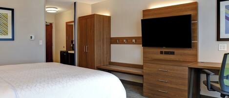 Una habitación de hotel con una cama, un escritorio con televisor de pantalla plana, una silla y un armario.