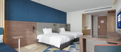 Een hotelkamer met twee bedden, een bureau, een stoel en een spiegel.
