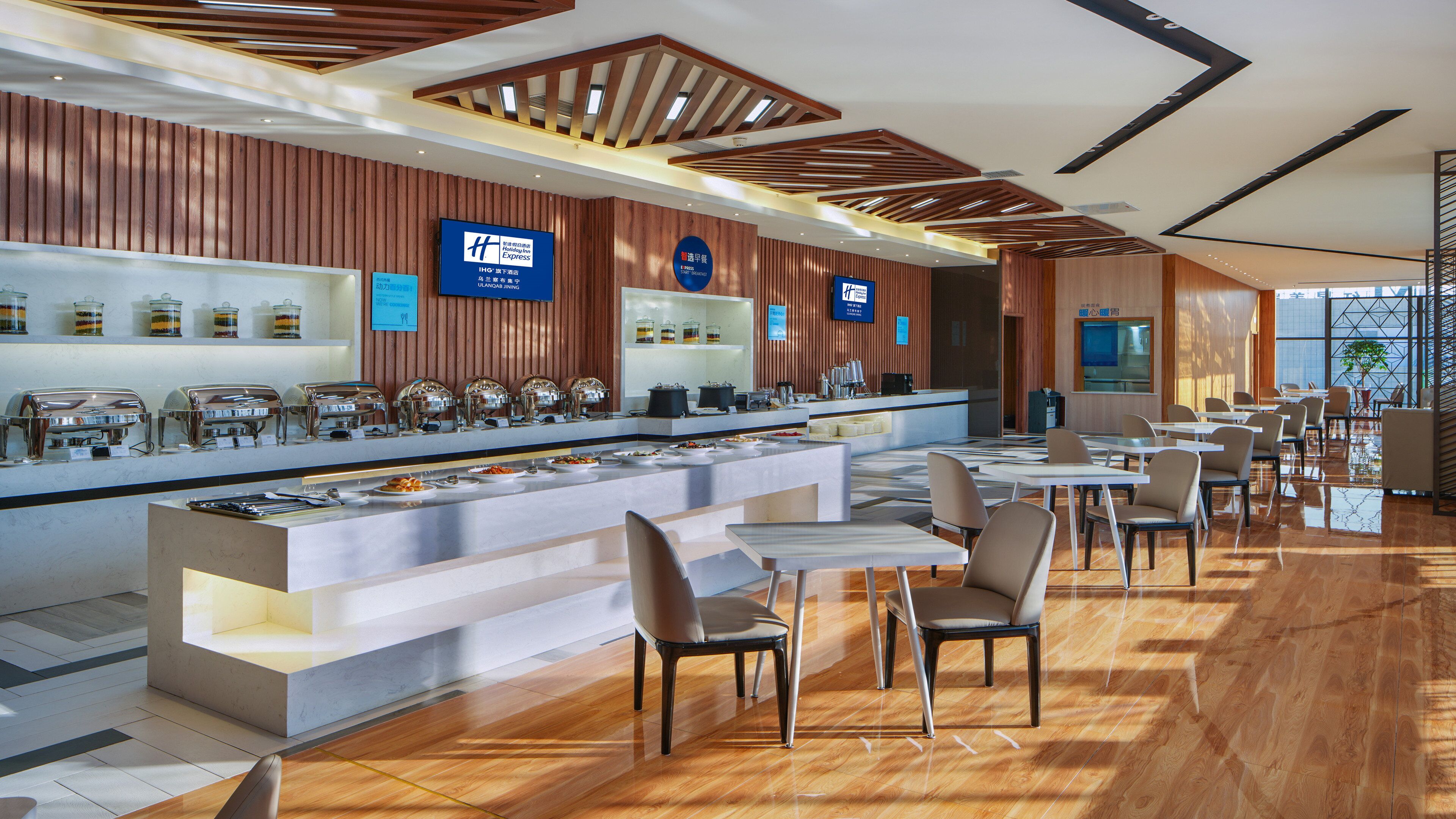 A hotel restaurant with a buffet setup, seating area, and a modern interior design.