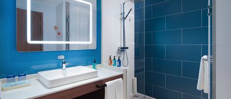 A modern bathroom with a large mirror, a white sink, and a shower area.