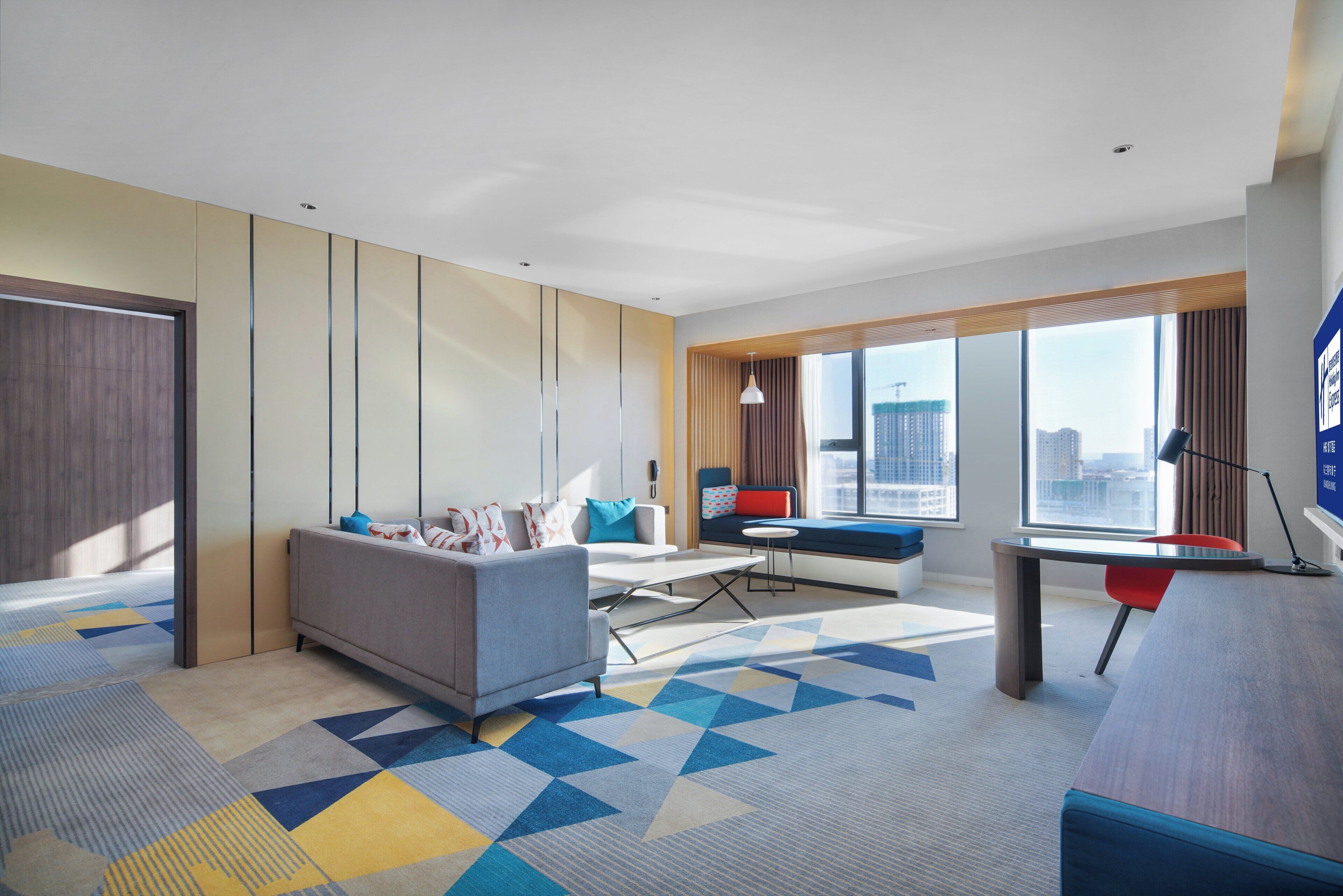 Une chambre d’hôtel moderne, dotée d’un canapé, d’un bureau et offrant une vue sur la ville.