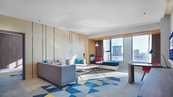 Une chambre d’hôtel moderne, dotée d’un canapé, d’un bureau et offrant une vue sur la ville.