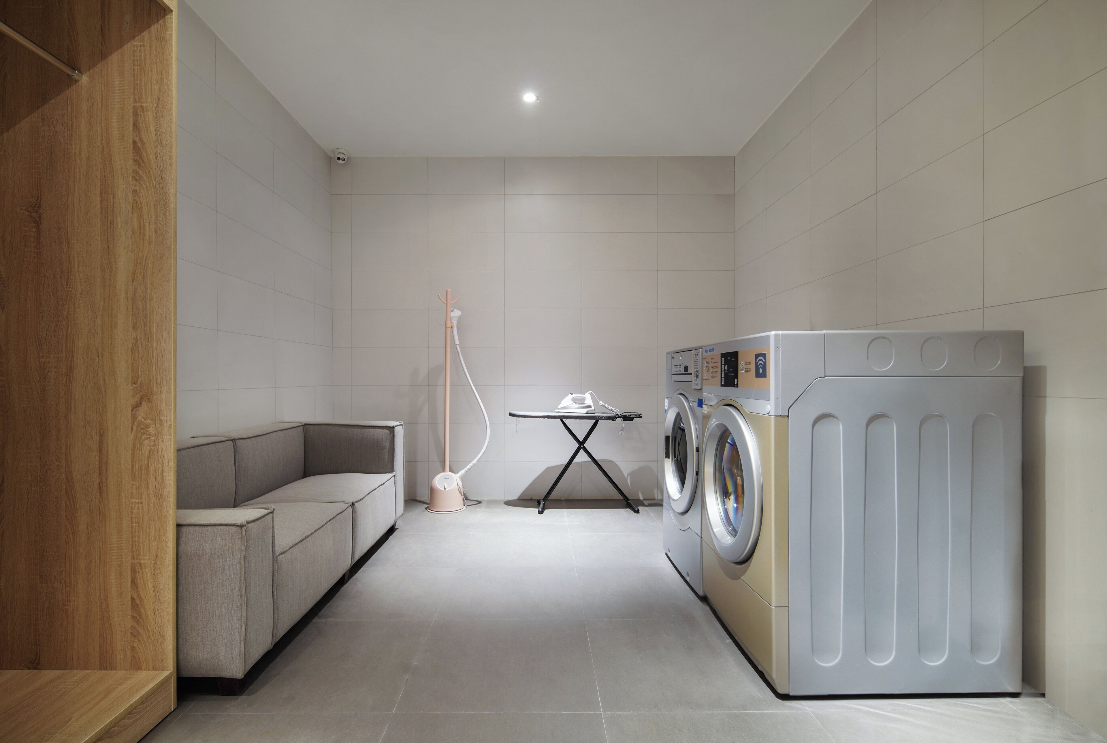 A laundry room with a washing machine, a drying rack, and a folding table.
