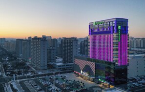 A multi-story hotel with a prominent vertical light display on the facade. - Holiday Inn Express Ulanqab Jining by IHG (Ulaan Chab)