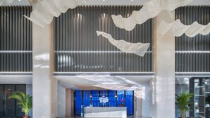 A modern hotel lobby with a reception desk, potted plants, and hanging decorative elements. - Holiday Inn Express Ulanqab Jining by IHG (Ulaan Chab)
