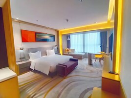 A modern hotel room with a large bed, bedside tables, a desk, and a chair.