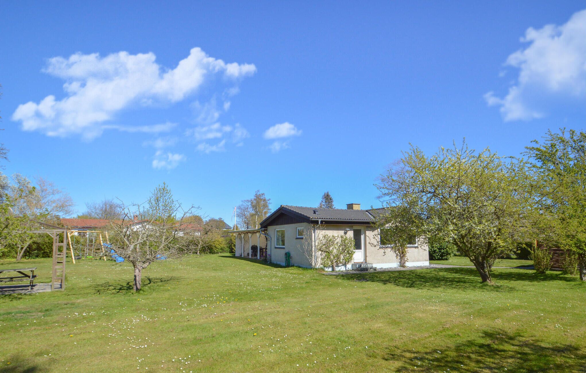 Une maison avec un jardin, une balançoire et une table de pique-nique.